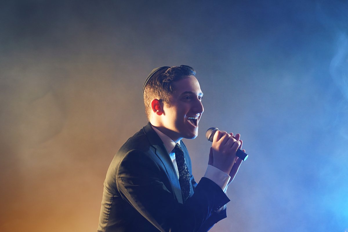 Dovid Pearlman singing under blue stage light